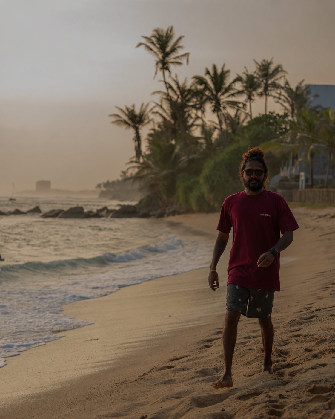 Surf school owner walking on Madiha beach at sunset